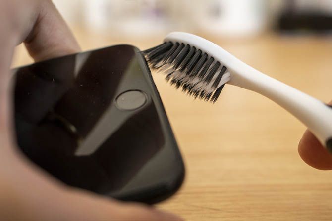 Чистка микрофона и динамика iPhone с помощью зубной щетки