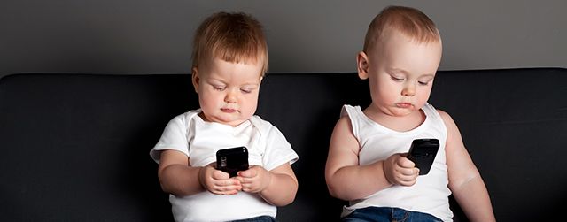 маленький мальчик и девочка играют с мобильными телефонами