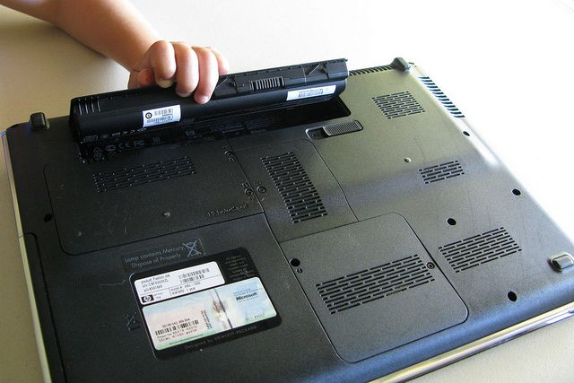 Ребенок, удаляющий батарею ноутбука