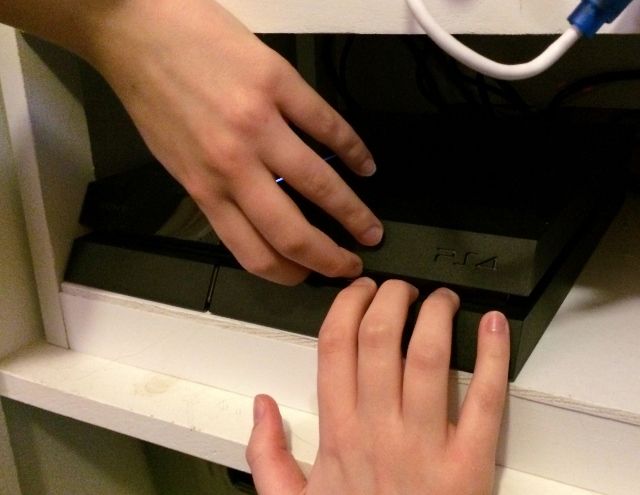 Пальцы пытаются открыть PlayStation 4