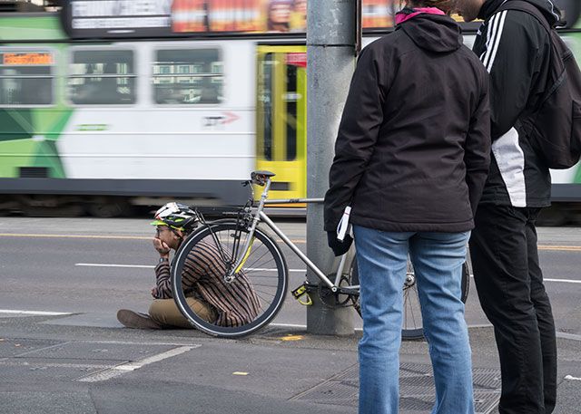 Быстро движущийся трамвай позади велосипедиста, сидящего на земле
