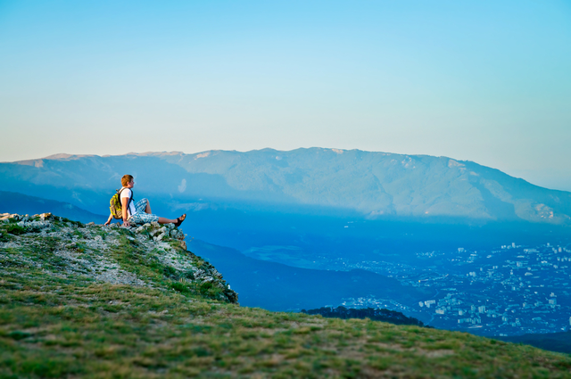 6 молодых туристов с рюкзаком сидят на холме и наслаждаются пейзажем